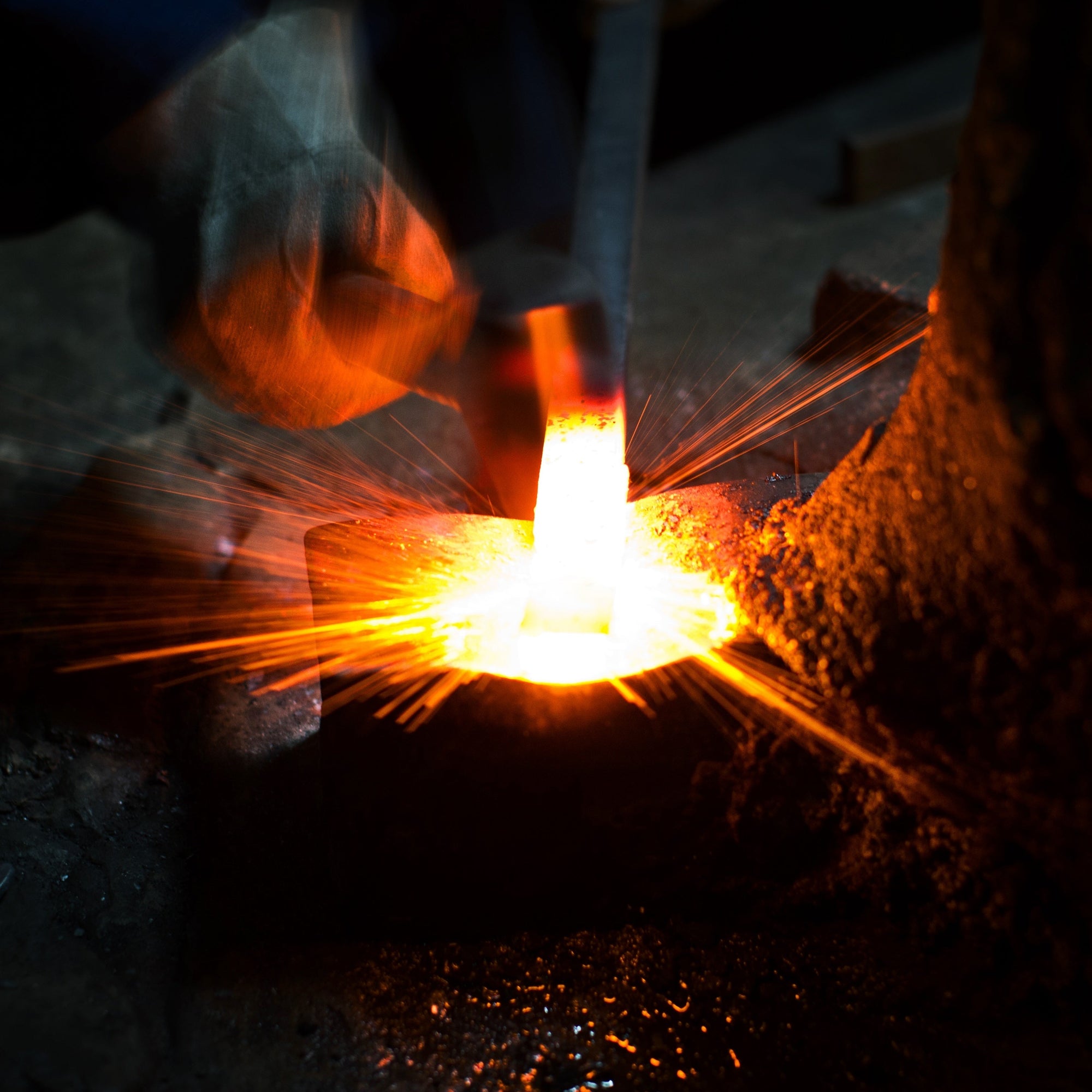 a hammer striking red hot steel