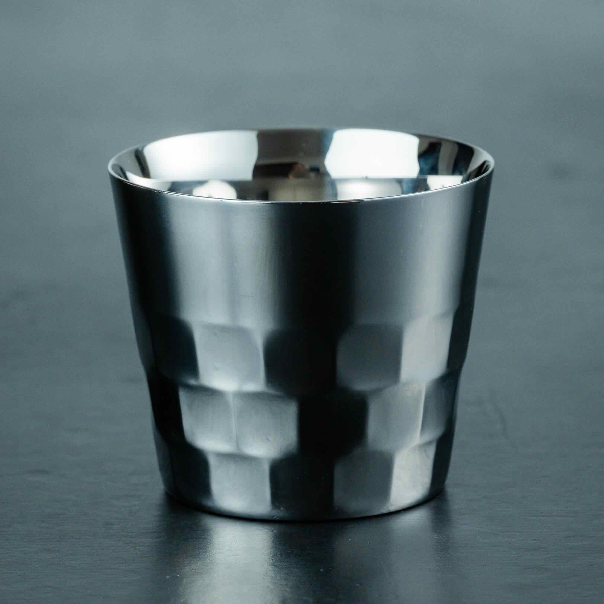 Metallic silver cup with geometric pattern on a dark gray background