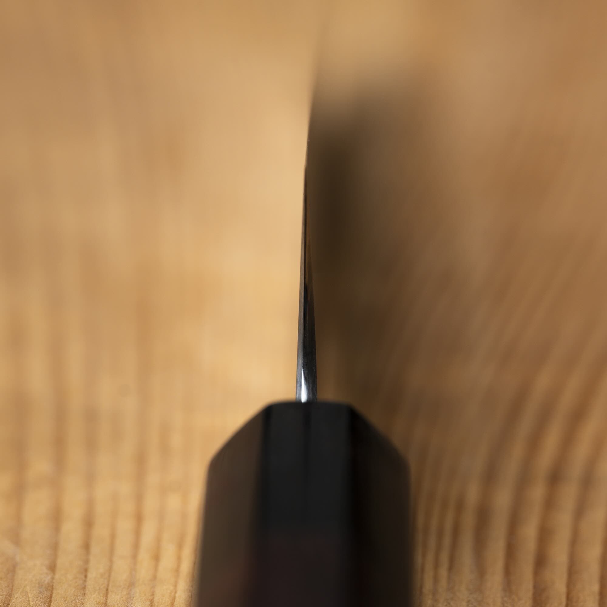 close up up knife blade on a wooden surface